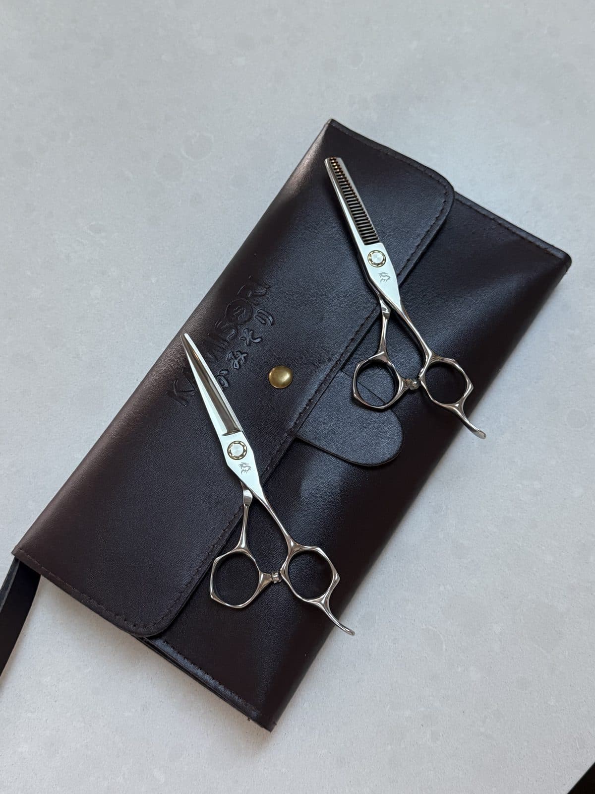 Professional barber scissors resting on a leather pouch